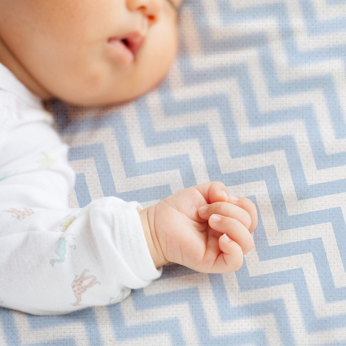 Baby sleeping on blue chevron change pad sheet 